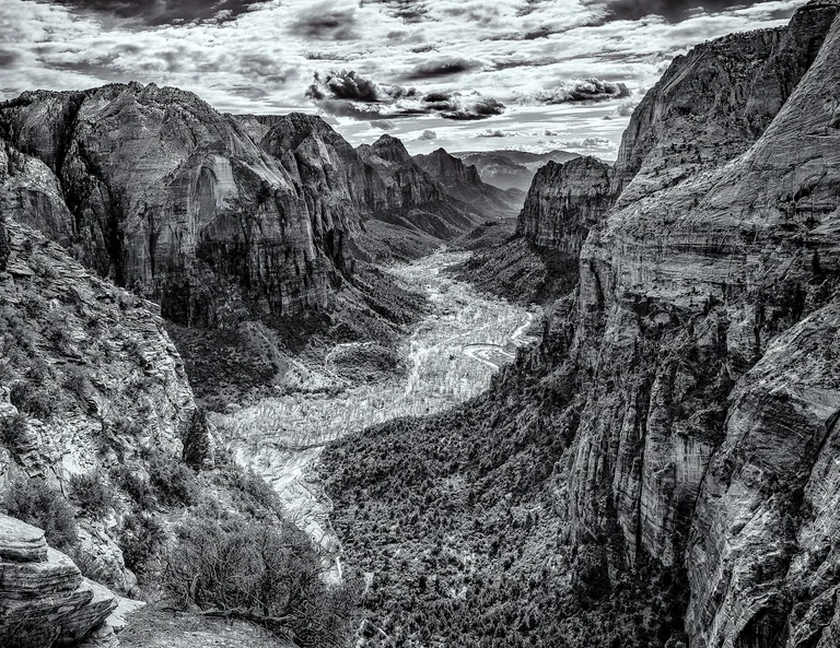 Black-and-white view into a deep canyon, with a winding river beneath steep rock walls.