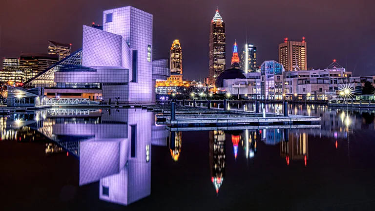 Cleveland’s illuminated waterfront and the Rock and Roll Hall of Fame reflected in still water.