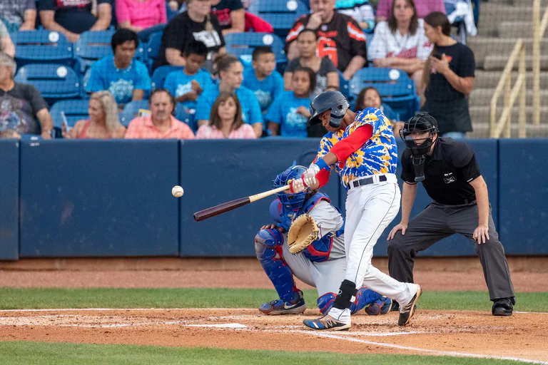 Batter, catcher, and umpire line up at home plate during a pitch.