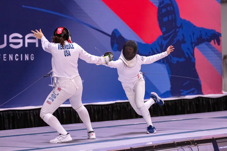 Two masked fencers pass at close range with their arms extended.