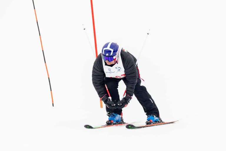 A skier crouches low over parallel skis with poles trailing behind.
