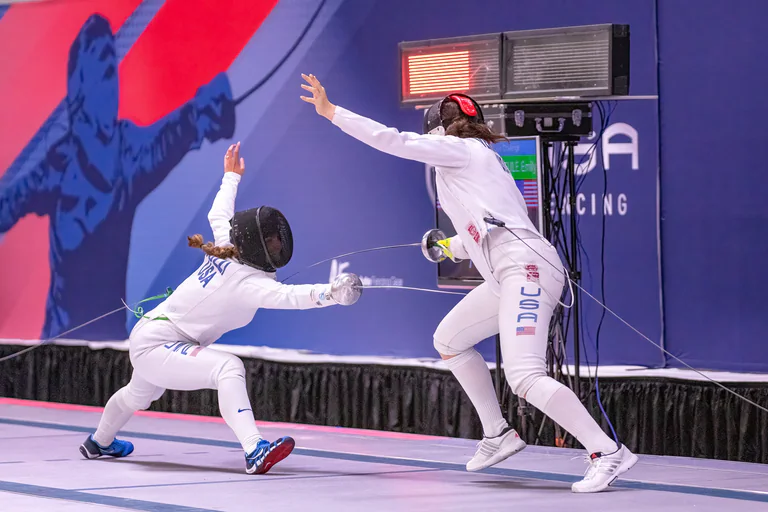 One fencer lunges low as an opponent springs backward with an arm raised.